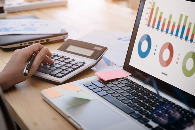 a person using a calculator and working on a laptop